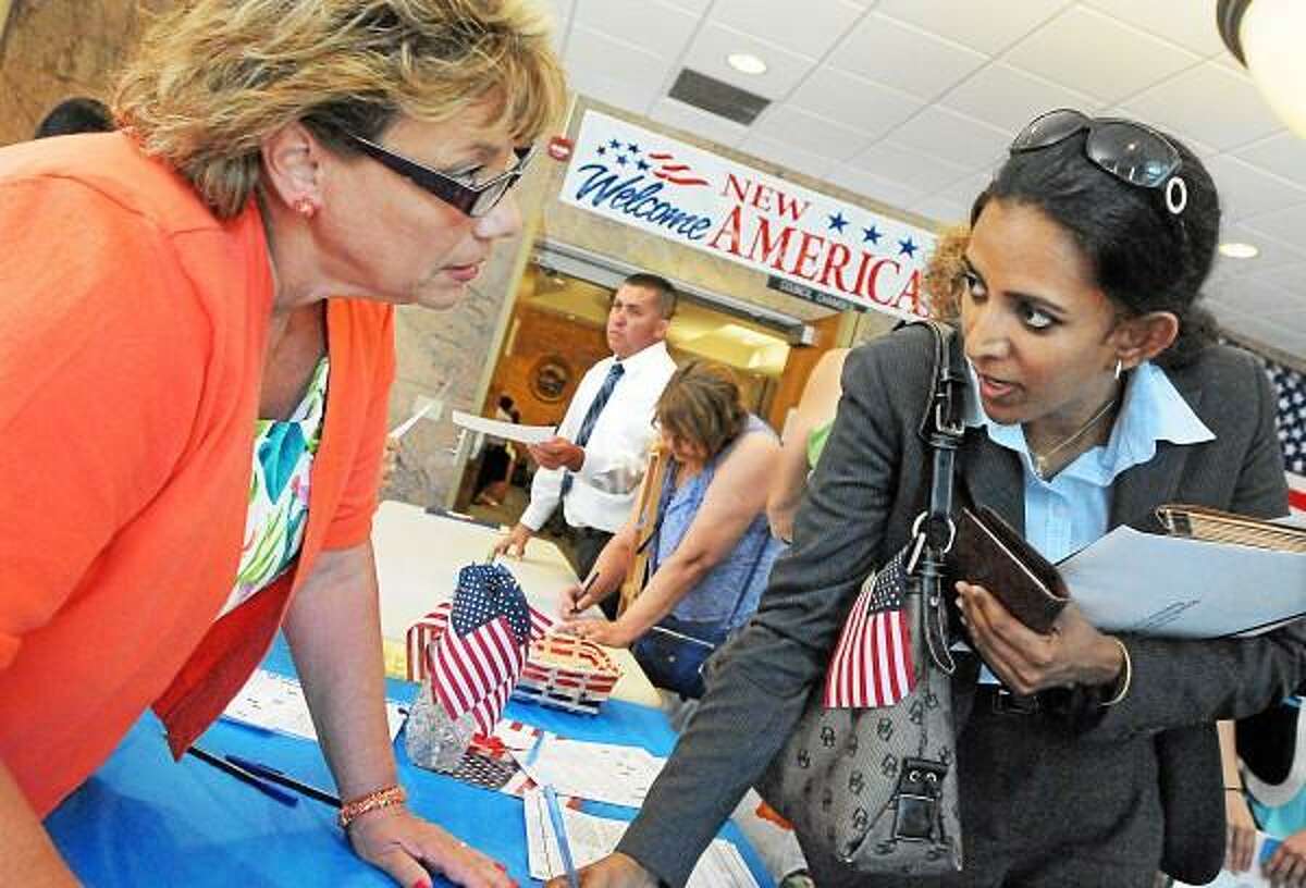 Catherine Avalone - The Middletown Press Republican Registrar of Voters Janice A. Gionfriddo registers Stamford resident Lakshmi Dharmarajan, at right, of India to vote after becoming a U.S. citizen at the Naturalization Ceremony Wednesday afternoon in the council chambers at City Hall in Middletown.