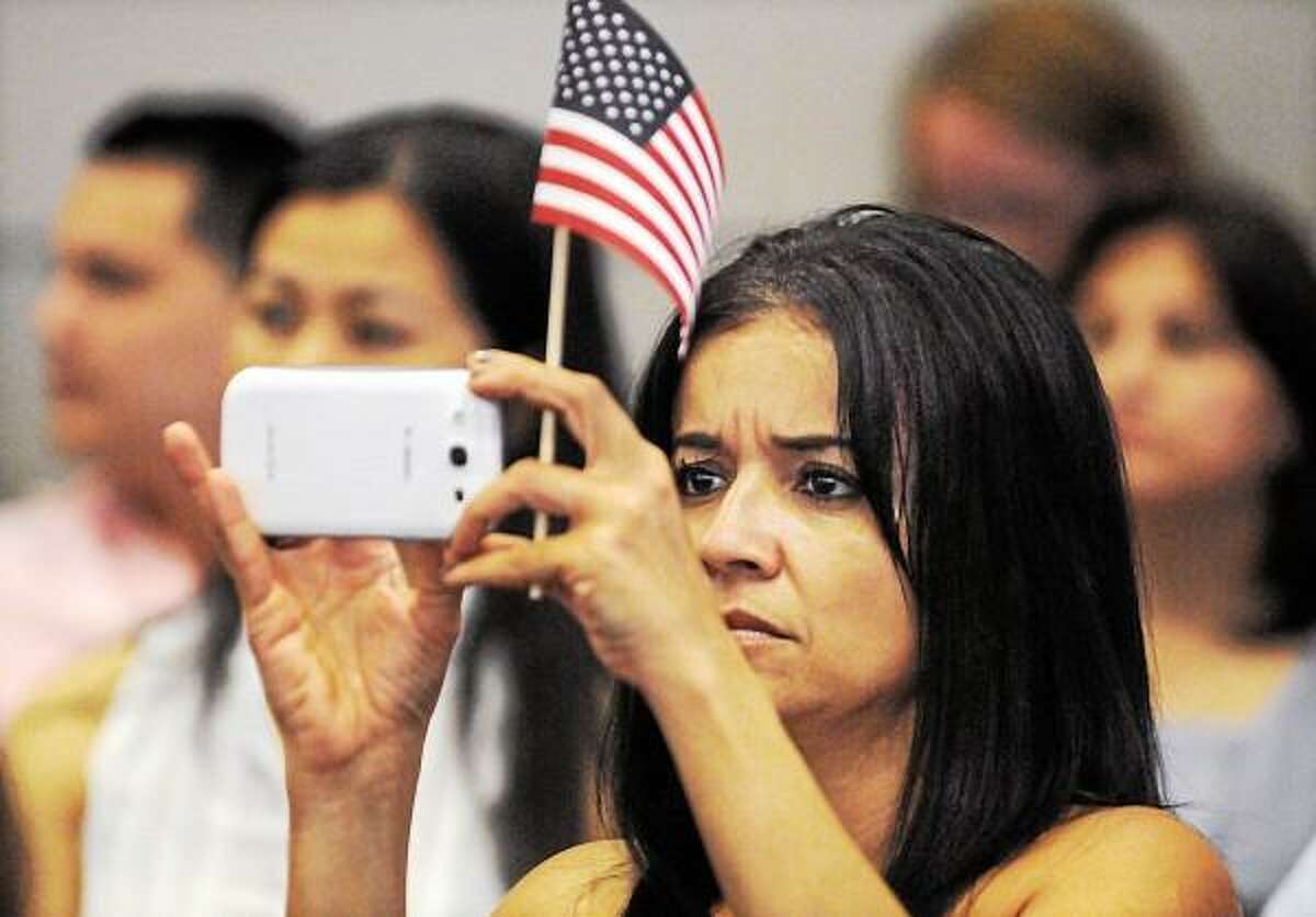 Catherine Avalone - The Middletown Press Norwalk resident Liliana Catano from Columbia uses her smart phone to make a video of Judge Stefan R. Underhill of the U.S. District Court speak shortly after becoming a U.S. citizen at the Naturalization Ceremony held Wednesday afternoon in the council chambers at City Hall in Middletown.