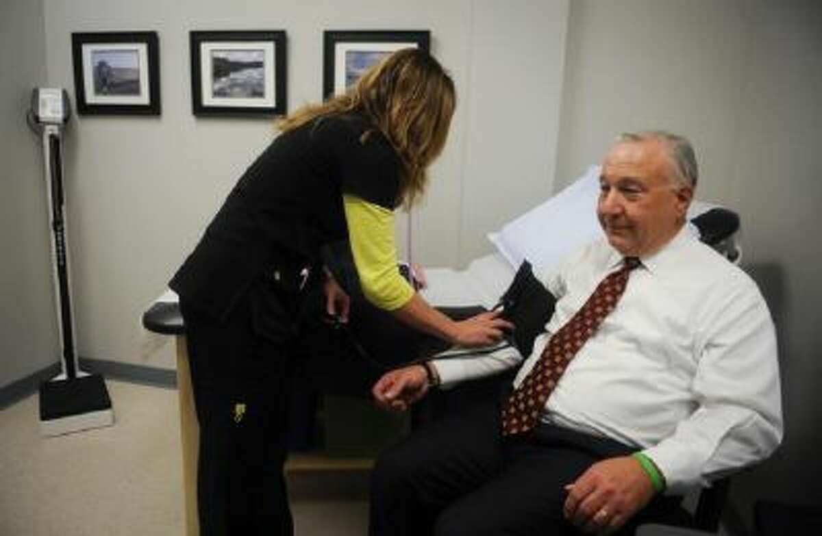 Lisa Trever takes the blood pressure of AlloSource CEO Tom Cycyota at the firm's on-site health clinic.