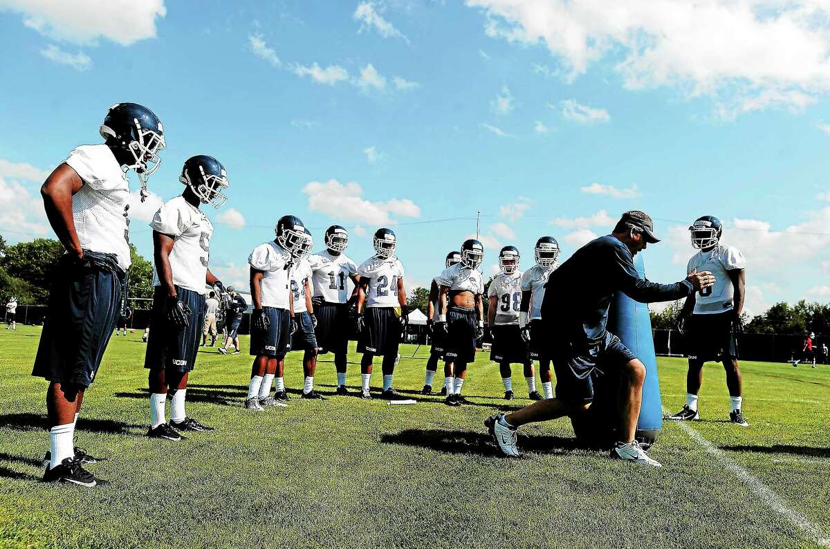UConn offensive coordinator T.J. Weist demonstrates a drill during practice in Storrs on Aug. 2.