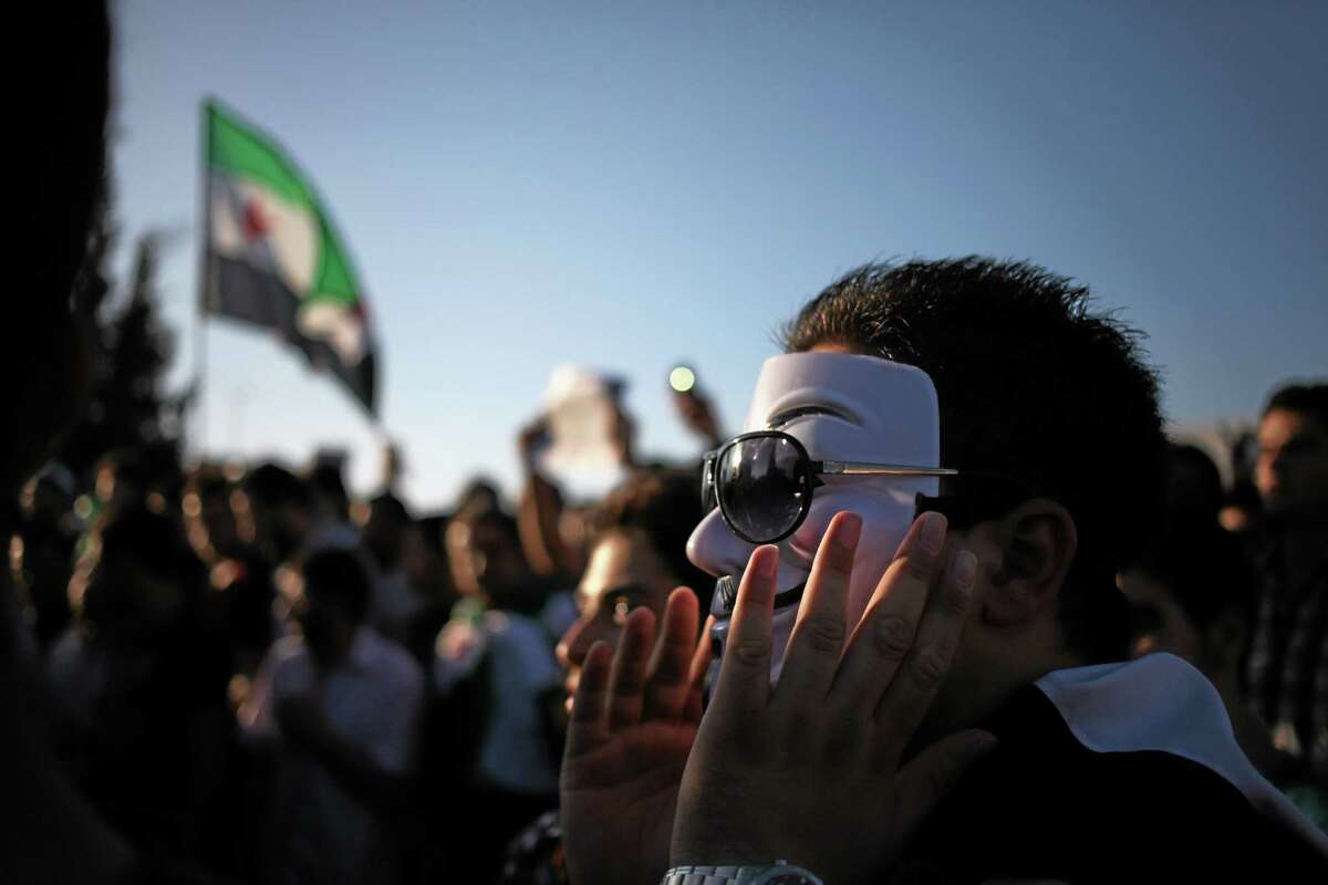 A Syrian protester wears a Guy Fawkes mask and chants slogans against Syrian President Bashar Assad, during a protest in front of the Syrian embassy in Amman, Jordan, to condemn the alleged poison gas attack on the suburbs of Damascus, Friday, Aug. 23, 2013. Anti-government activists accused the Syrian regime of carrying out a toxic gas attack that is thought to have killed at least 100 people, including many children as they slept, during intense artillery and rocket barrages Wednesday on the eastern suburbs of Damascus.