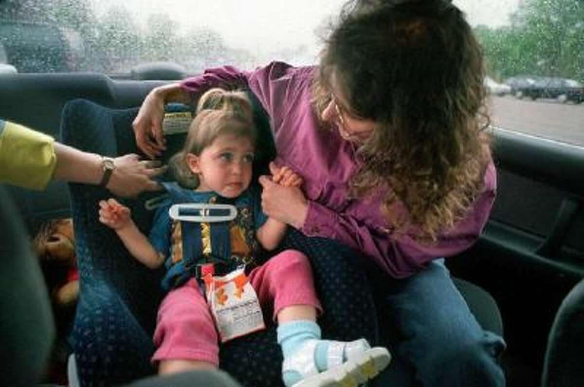 Stacy Segal checks the belts on the car seat holding her daughter, Jamie Hanson, 2. Segal is a child passenger safety specialist who helps parents insure that their child car seats are installed properly.