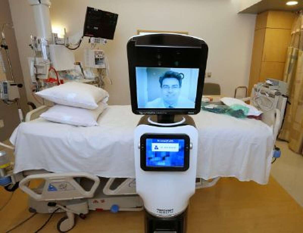 In this photo taken Wednesday, Nov. 6, 2013, Dr. Alan Shatzel, medical director of the Mercy Telehealth Network, is displayed on the monitor RP-VITA robot at Mercy San Juan Hospital in Carmichael, Calif. The robots enable physicians to have a different bedside presence as they "beam" themselves into hospitals to diagnose patients and offer medical advice during emergencies.