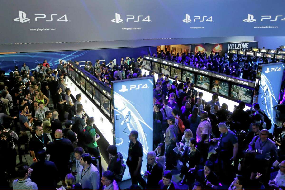 FILE - In this June 11, 2013 file photo, show attendees play video games on the new Sony PlayStation 4 at the Sony booth during the Electronic Entertainment Expo, in Los Angeles. Twitch is coming to the PlayStation 4; the popular streaming video service that allows gamers to broadcast footage online was previously announced as a feature for Microsoft’s Xbox One. Sony said Tuesday, Aug. 20, 2013, the service would also be available on the PS4, which adds a “Share” button to its new controller. (AP Photo/Jae C. Hong, File)