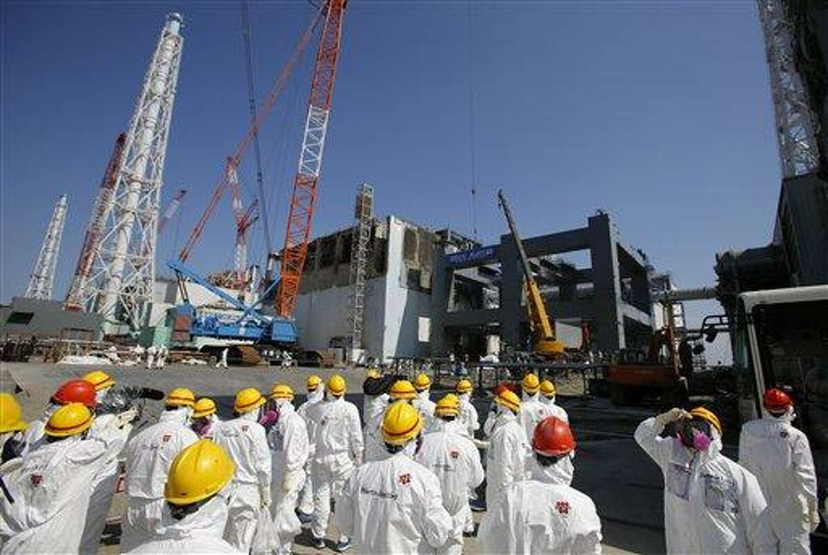 AP FILE - In this March 6, 2013 file photo, journalists wearing protective gears are escorted to the damaged No. 4 reactor building and an under construction foundation, center right, which will store the reactor's melted fuel rods, at Tokyo Electric Power Co.'s crippled Fukushima Dai-ichi nuclear power plant in Okuma town, Fukushima prefecture, northeast of Tokyo. The cooling system failed for a storage pool for fuel at one of the reactors at the tsunami-damaged nuclear plant in northeastern Japan Friday, April 5, 2013, - the second in a month, although there was no immediate danger from the breakdown. (AP Photo/Issei Kato, File)