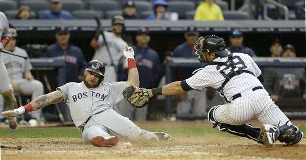 Boston Red Sox Jonny Gomes, left, scores on a ninth-inning error by New York Yankees second baseman Robinson Cano (not shown) in an opening day baseball game at Yankee Stadium in New York, Monday, April 1, 2013. (AP Photo/Kathy Willens)