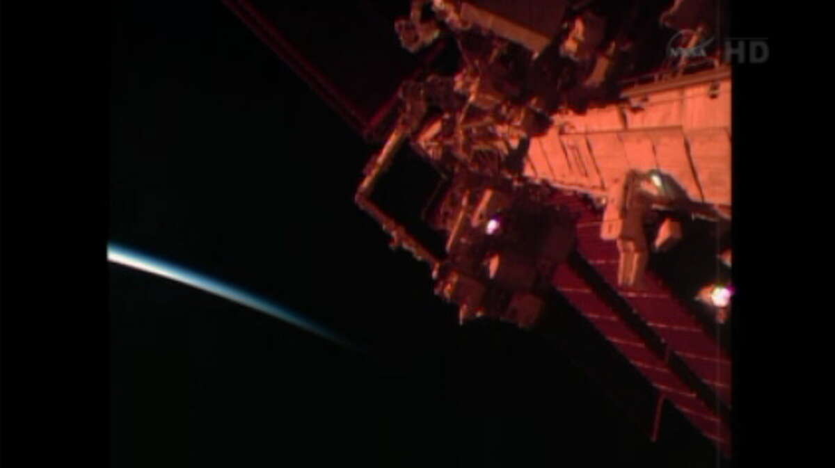 Connecticut Astronaut Rick Mastracchio, of Waterbury, makes his way along the ISS truss on the right as an orbital sunrise begins over Earth to the left (NASA).