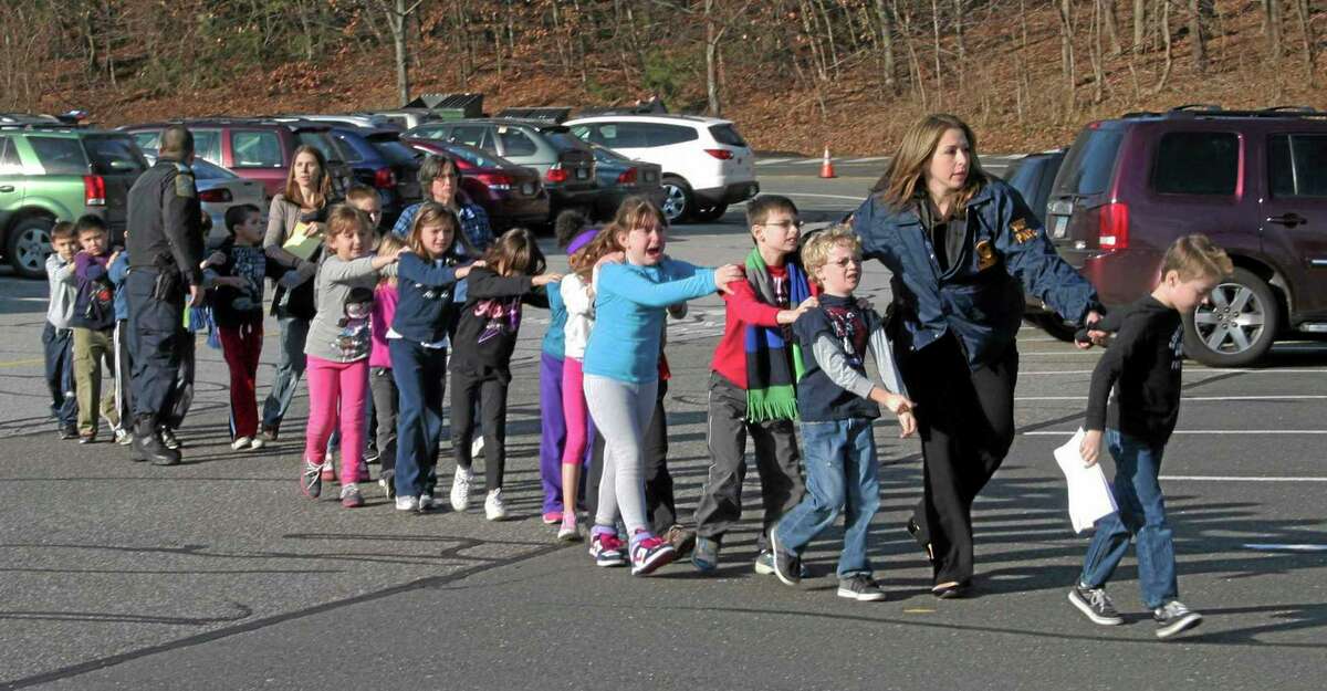 FILE - In this Dec. 14, 2012 file photo provided by the Newtown Bee, Connecticut State Police lead a line of children from the Sandy Hook Elementary School in Newtown, Conn., where gunman Adam Lanza opened fire, killing 26 people, including 20 children. (AP Photo/Newtown Bee, Shannon Hicks, File) MANDATORY CREDIT: NEWTOWN BEE, SHANNON HICKS