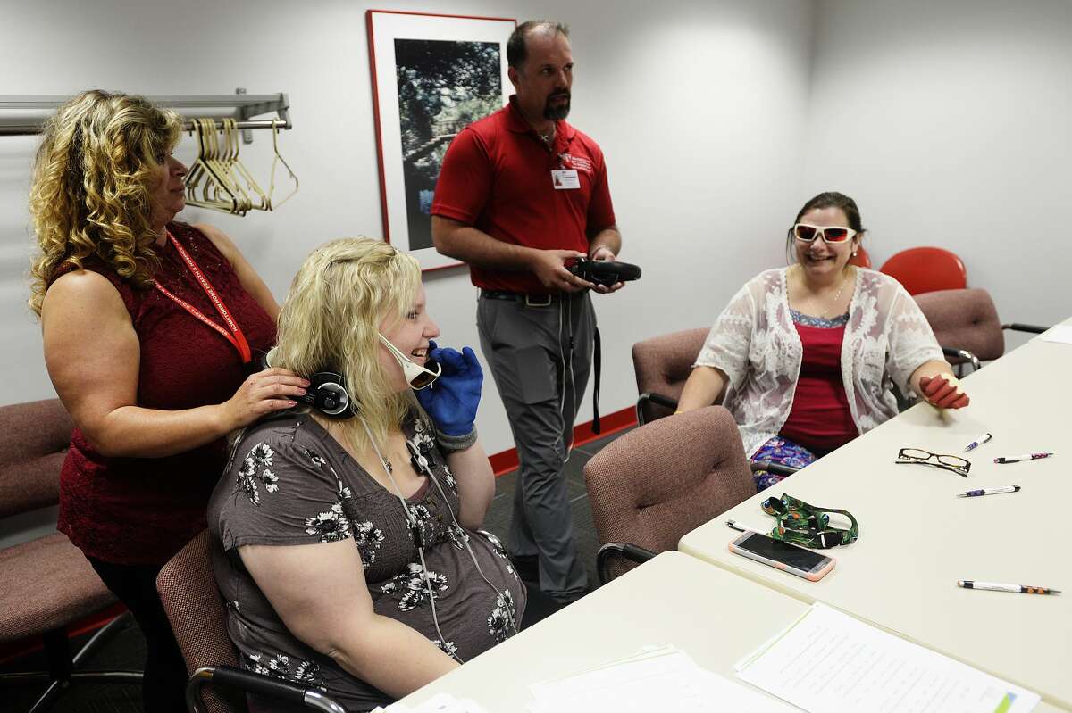 Erin Sorensen of Midland, second from left, and Sandy Banks of Midland, far right, prepare to participate in a virtual simulation on what individuals with Dementia experience in their day to day lives hosted by The Arc of Midland, with the help of Midland Patient Care Coordinator Nichole Bliss, far left, and Genesee County Patient Care Coordinator Nathan Ross, second from right, on Wednesday, August 16, 2017 at The Arc of Midland.