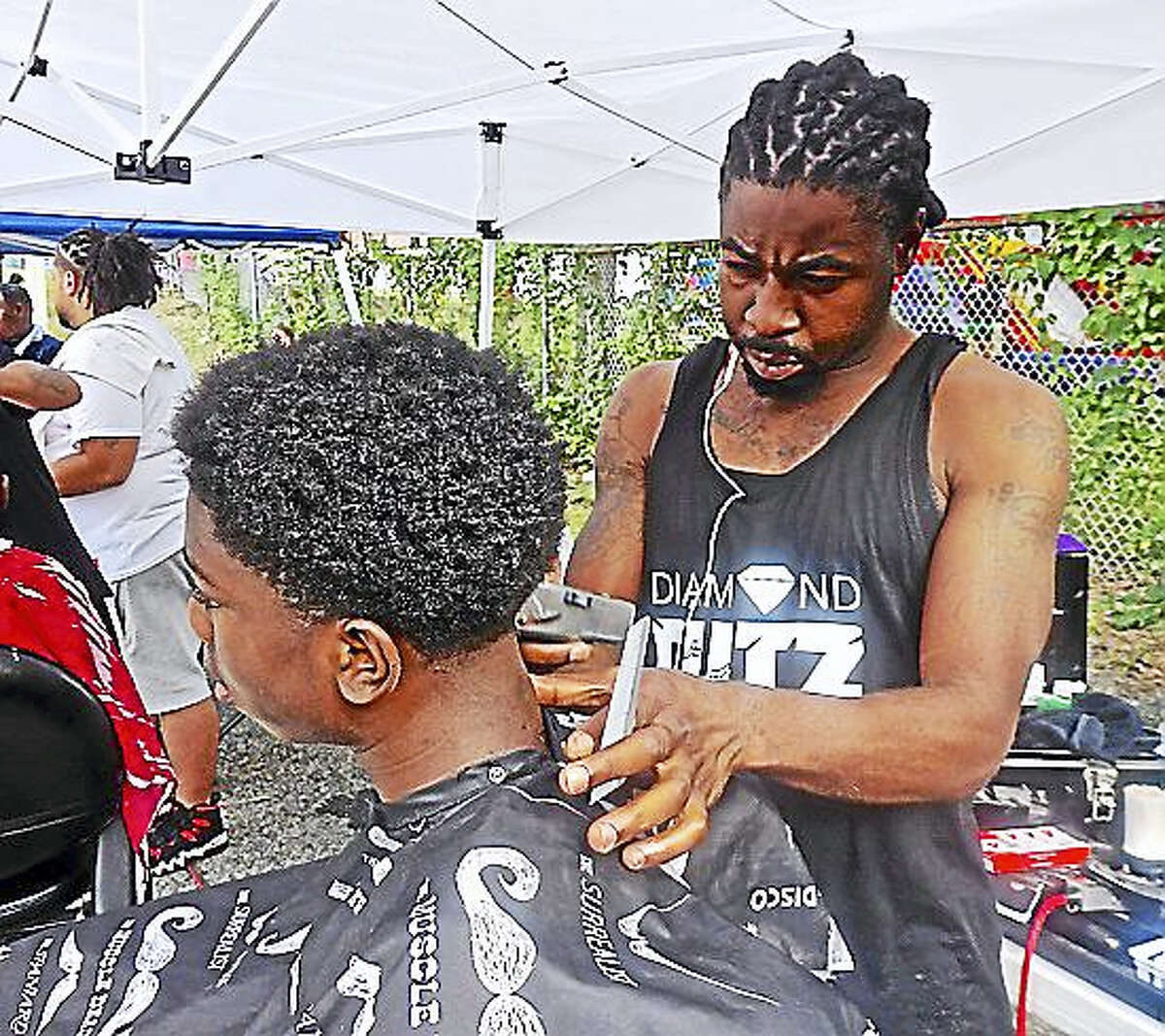 Diamond Cutz owner T.J. Green giving haircut to Jymere Jones at past rally.