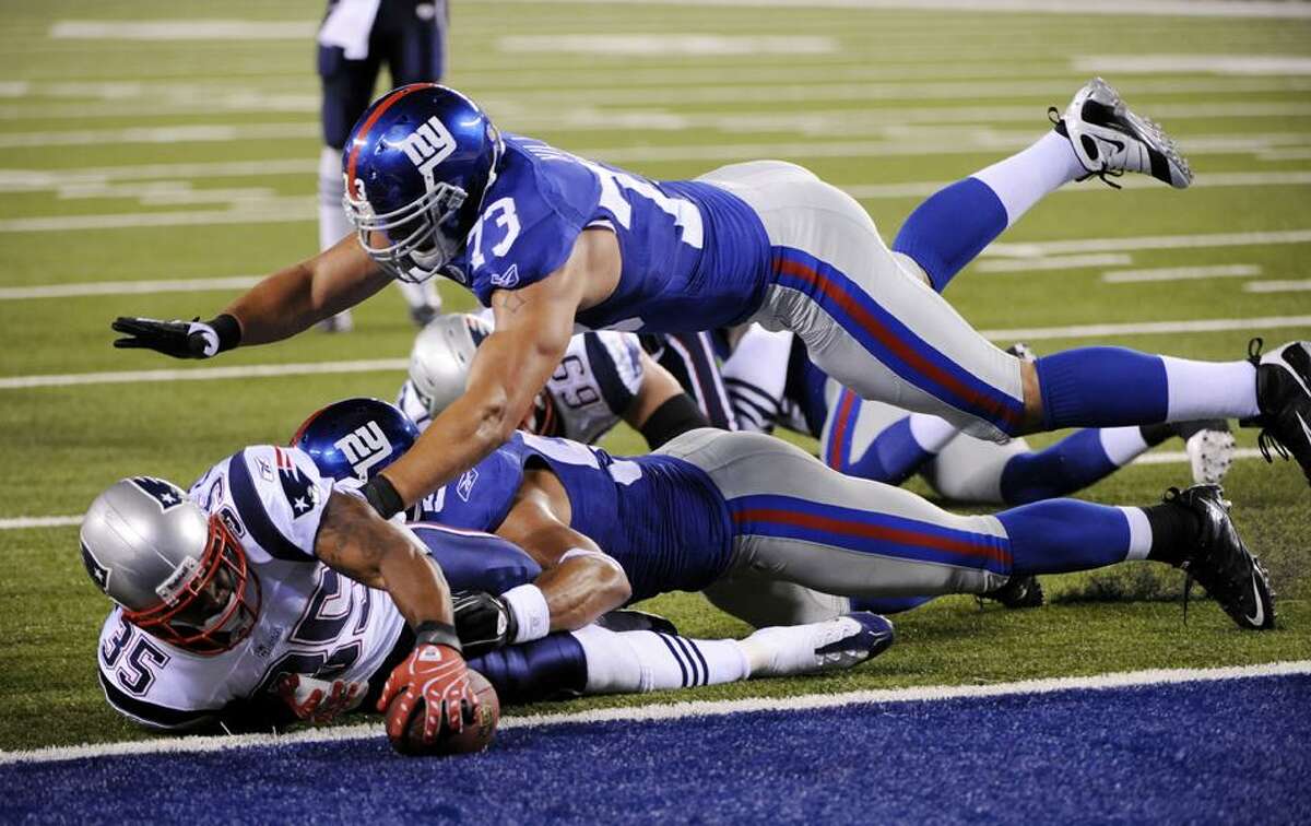 New England Patriots Thomas Clayton, left, is stopped at the goal line by New York Giants' Bryan Kehl, second form left, and Tommie Hill, top, during the third quarter of the NFL preseason football game at New Meadowlands Stadium in East Rutherford, N.J., Thursday. (AP Photo/Bill Kostroun)