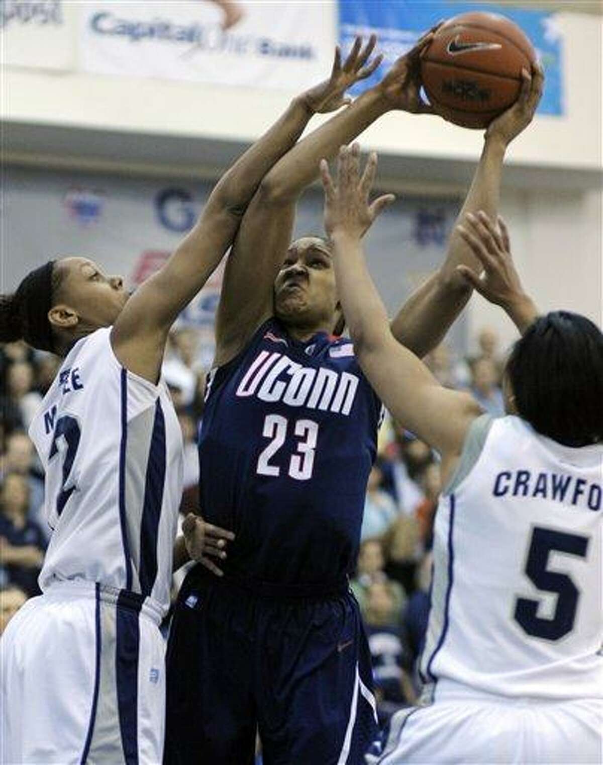 Connecticut forward Maya Moore, 23, center, is tied-up by Georgetown forwards Tia Magee, 2, left, and Adria Crawford during the first period of their Big East game in Washington, Saturday, Feb. 26, 2011. (AP Photo/Cliff Owen)