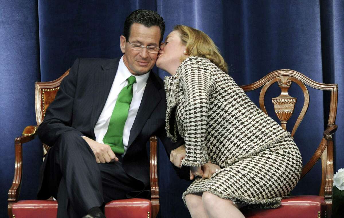In this Jan. 5, 2011 file photo, Gov. Daniel P. Malloy gets a kiss from his wife Cathy while "Danny Boy" is played during his inauguration ceremony in Hartford Conn. The new first lady said Thursday, that she'll remain at her job as executive director of the Sexual Assault Crisis and Education Center in Stamford, but is looking for a new job in the Hartford area. (AP Photo/Sean D. Elliot, Pool, File)