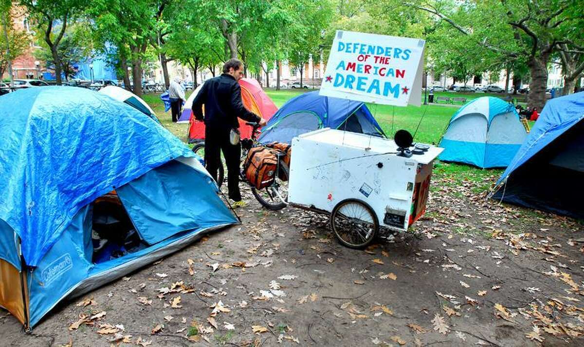Kenneth Manteau of Branford maneuvers his bicycle through tents at the Occupy New Haven protest on the New Haven Green. Arnold Gold/Register