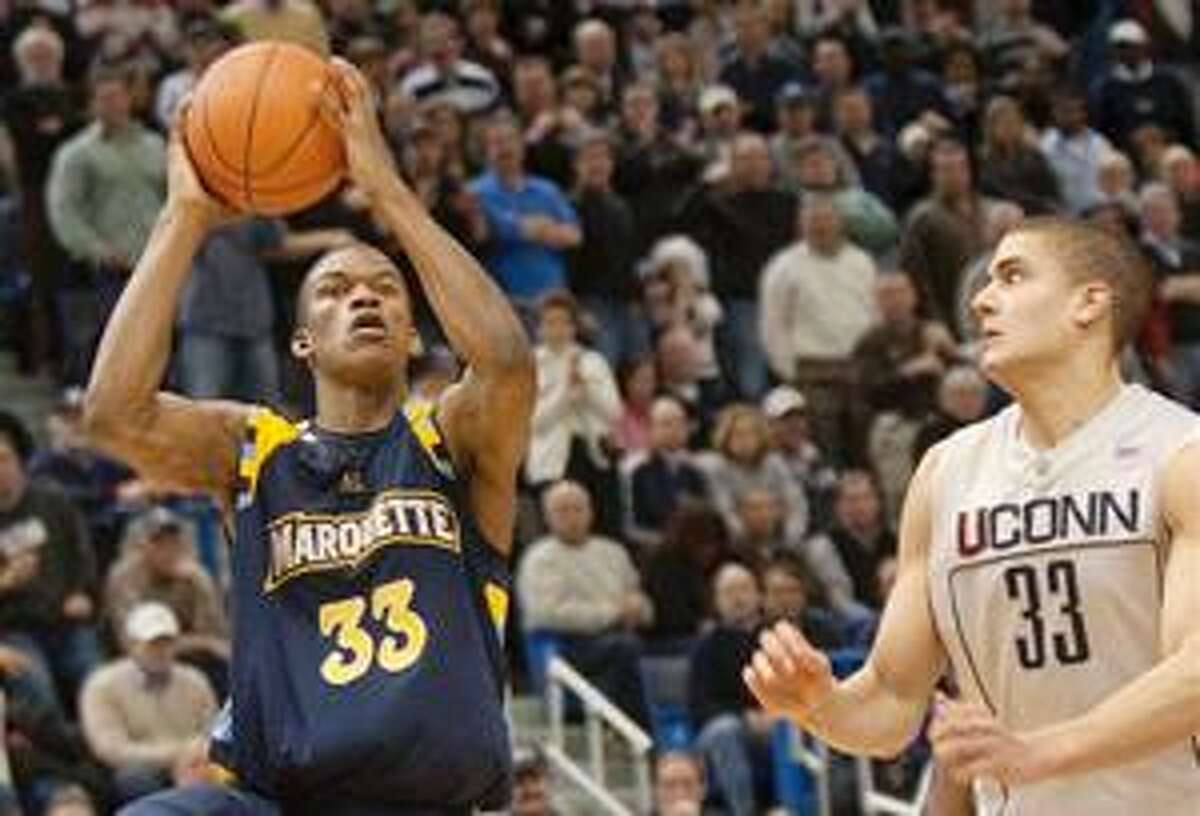 (AP) Marquette's Jimmy Butler, left, shoots the go-ahead basket in the closing seconds of Saturday's game as UConn's Gavin Edwards defends.