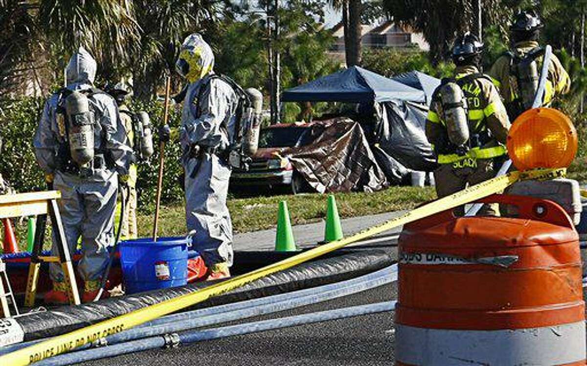 In this Feb. 15, 2011 photo, Palm Beach County firefighters in protective suits work near Jorge Barahona's pesticide truck, background, where it was found the night before along the side of Interstate 95 near West Palm Beach, Fla. The badly deteriorated body of Barahona's 10-year-old daughter was discovered in the truck hours after her critically injured twin brother was found having seizures in the front seat after being doused in acid by his father, according to officials. Barahona was lying on the ground near the truck with severe burns, apparently from gasoline he poured on himself. (AP Photo/Palm Beach Post, Richard Graulich)