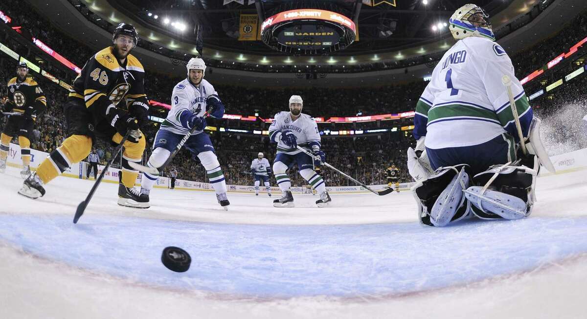 Vancouver Canucks goalie Roberto Luongo (1) looks for the puck as it crosses the goal line for the Bruins' second goal of the first period during Game 6 of the NHL hockey Stanley Cup Finals, Monday, June 13, 2011, in Boston. Bruins center David Krejci (46) and Vancouver's Kevin Bieksa (3) and Chris Higgins look on. (AP Photo/Elsa, Pool)