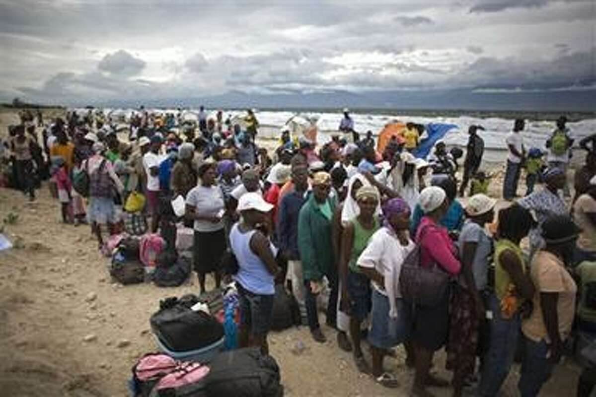 People wait in line to be evacuated from the Corail-Cesselesse tent refugee camp before the arrival of tropical storm Tomas in Port-au-Prince, Haiti, Thursday, Nov. 4, 2010. Fear and confusion set in among more than 1 million Haitians advised to leave earthquake homeless camps in the country's capital.(AP Photo/Ariana Cubillos)