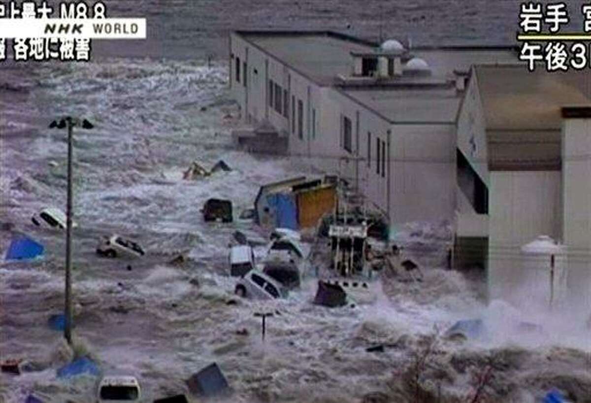 In this video image taken from Japan's NHK TV, a tsunami surge sweeps cars, boats and other debris against a building in Miyaku City, Iwate Prefecture Japan Friday March 11, 2011 following a massive earth quake. A magnitude 8.9 earthquake slammed Japan's northeastern coast Friday, unleashing a 13-foot (4-meter) tsunami that swept boats, cars, buildings and tons of debris miles inland. Fires triggered by the quake burned out of control up and down the coast. (AP PHOTO/NHK TV)