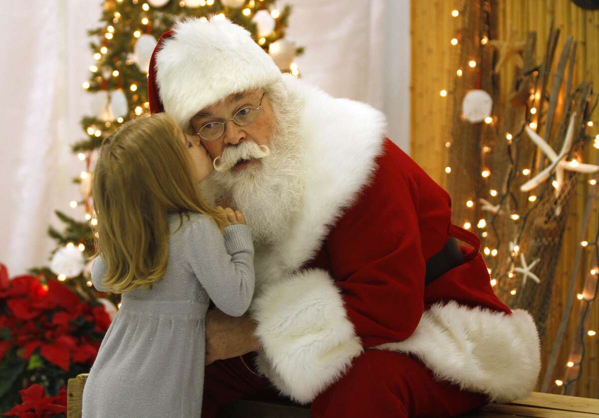 In this Nov. 30 photo, Santa, Cliff Snider, gets a kiss on the cheek from Bella Champion, 3, during a Christmas photo shoot at the "Beach Shack" in Emerald Isle, N.C. When Snider, who's been playing Santa since he was a teenager, gets a big-ticket request, he typically answers: "There's an awful lot of children asking for that this year. What else do you want?" (AP Photo/Tom Copeland)