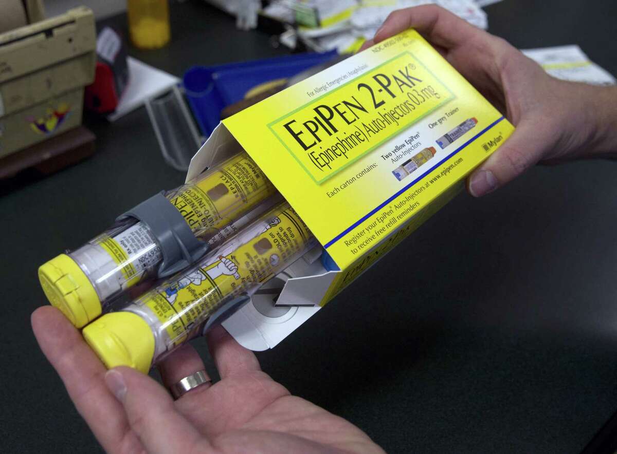 A pharmacist holds a package of EpiPens epinephrine auto-injector, a Mylan product, in Sacramento, Calif. Mylan has finalized a $465 million federal agreement settling allegations it overbilled Medicaid for its emergency allergy injectors for a decade.