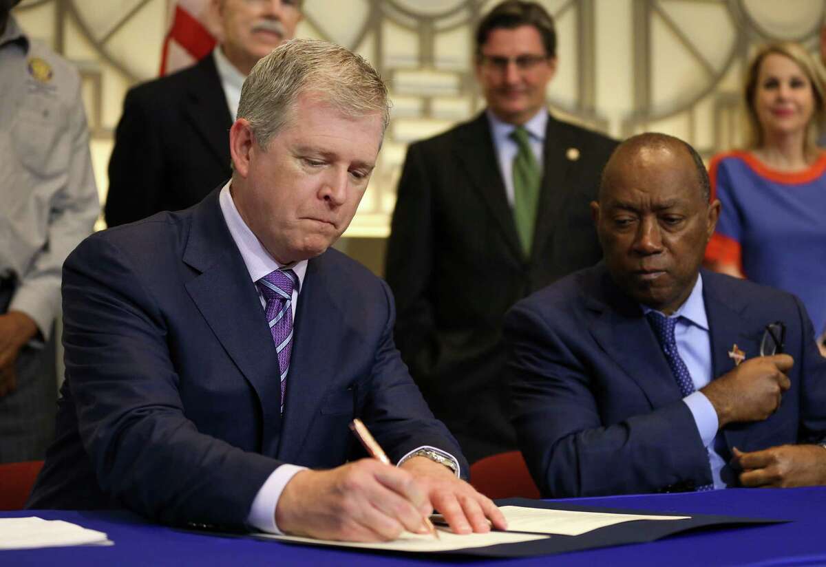 Texas Central Partners president Tim Keith, left, follows Houston Mayor Sylvester Turner in signing the memorandum of understanding for support of construction of a high-speed rail system that would connect the city with Dallas on Aug. 17.