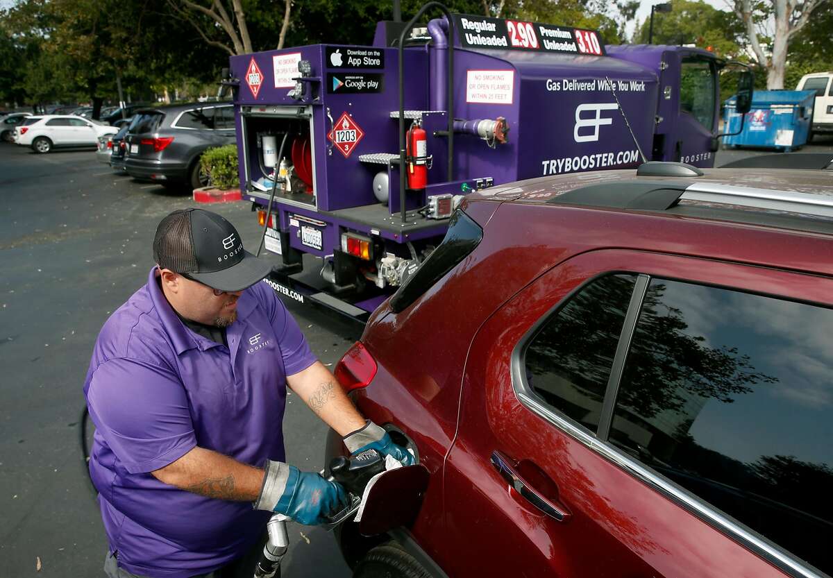 Cesar Guzman fills the gas tank of a car parked in the Technology Credit Union parking lot from his Booster mobile refueling truck in San Jose, Calif. on Friday, Aug. 11, 2017.