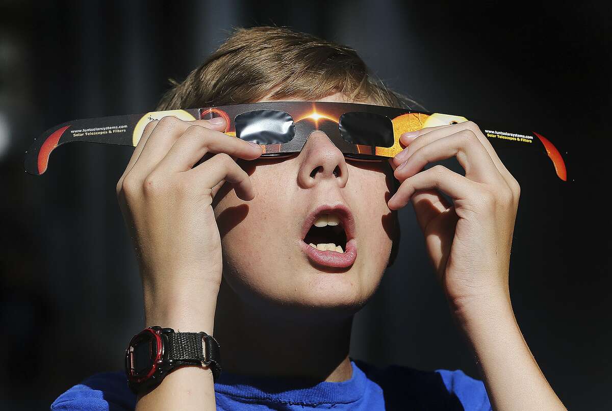 Colton Hammer tries out the new eclipse glasses he bought at the Clark Planetarium in Salt Lake City.