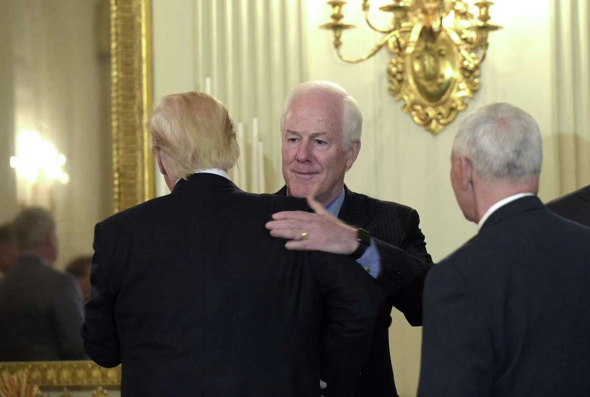 President Donald Trump, left, hugs Senate Majority Whip Sen. John Cornyn, R-Texas., center, as Vice President Mike Pence, right, watches, as they arrive for a reception for House and Senate leaders in the the State Dining Room of the White House in Washington, Monday, Jan. 23, 2017. (AP Photo/Susan Walsh)