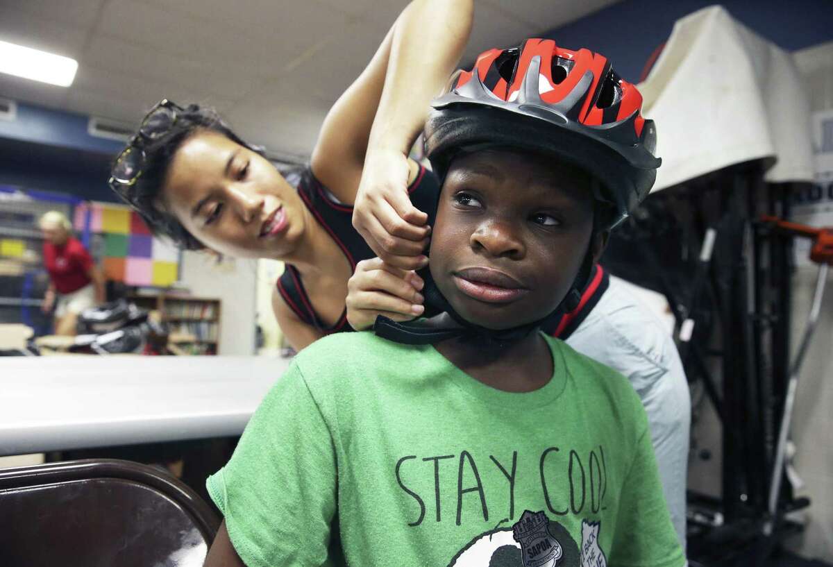 Volunteer Rose Ann Huynh fits gear on 8th grader Kodgo Sikouvi as kids get backpacks and bicycle helmets as well school supplies and vaccinations at the Garza Community Center back to school fair as on August 19, 2017.