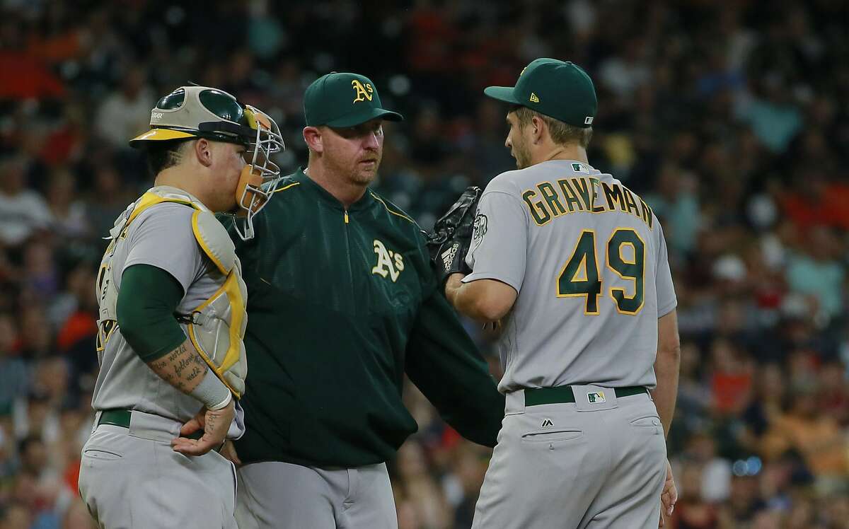 Oakland Athletics catcher Bruce Maxwell, left, and pitching coach Scott Emerson, center, talk with pitcher Kendall Graveman as he faces the Houston Astros with the bases loaded in the fourth inning of a baseball game Saturday, Aug. 29, 2017, in Houston. (AP Photo/Richard Carson)