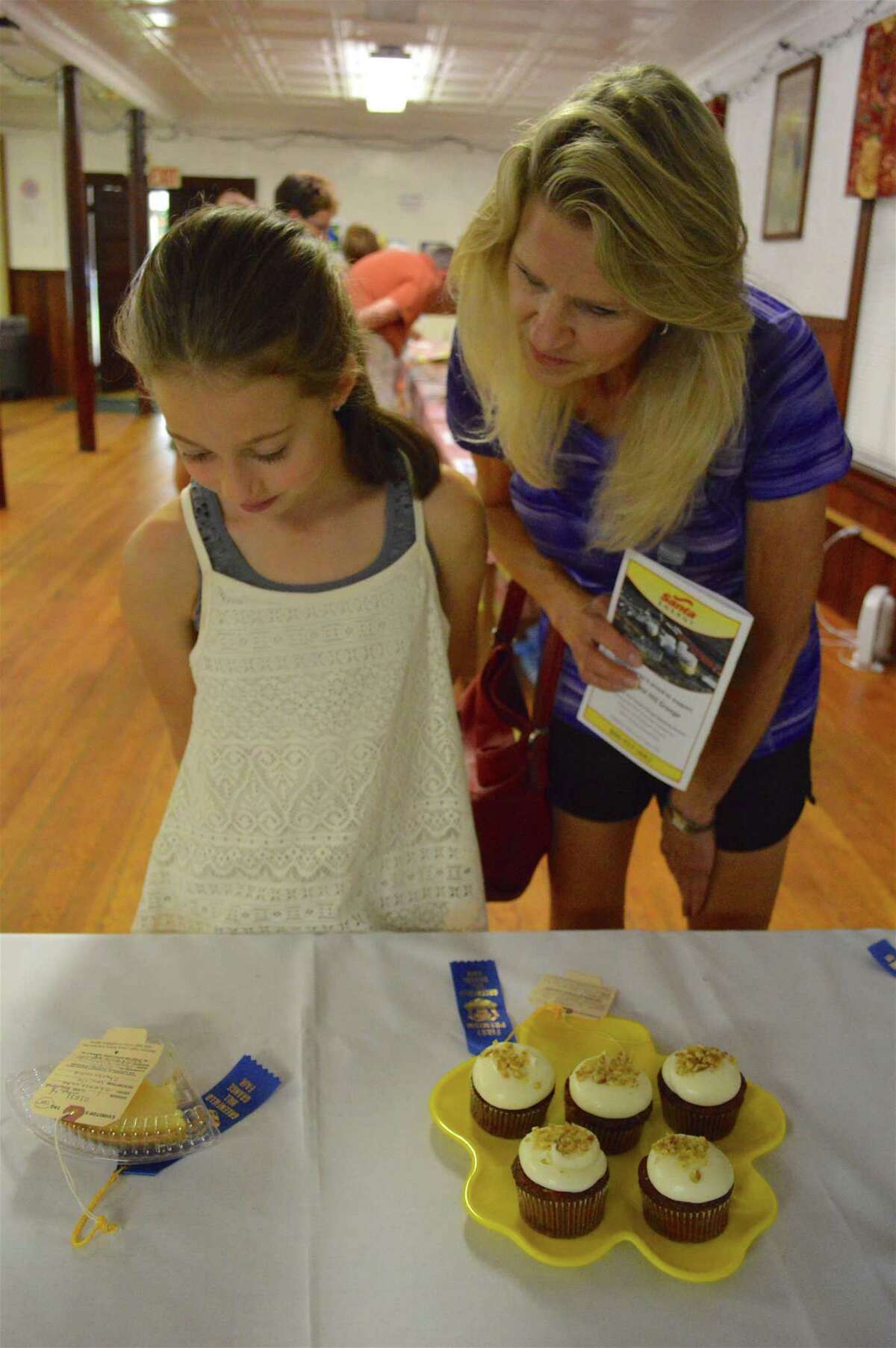 Bella Lombardi, 9, of Fairfield, and Pamela Cotter of Trumbull take a look at some prize-winning desserts at the Greenfield Hill Grange Hall Agricultural Fair, Saturday, Aug. 20, 2017, in Fairfield, Conn.