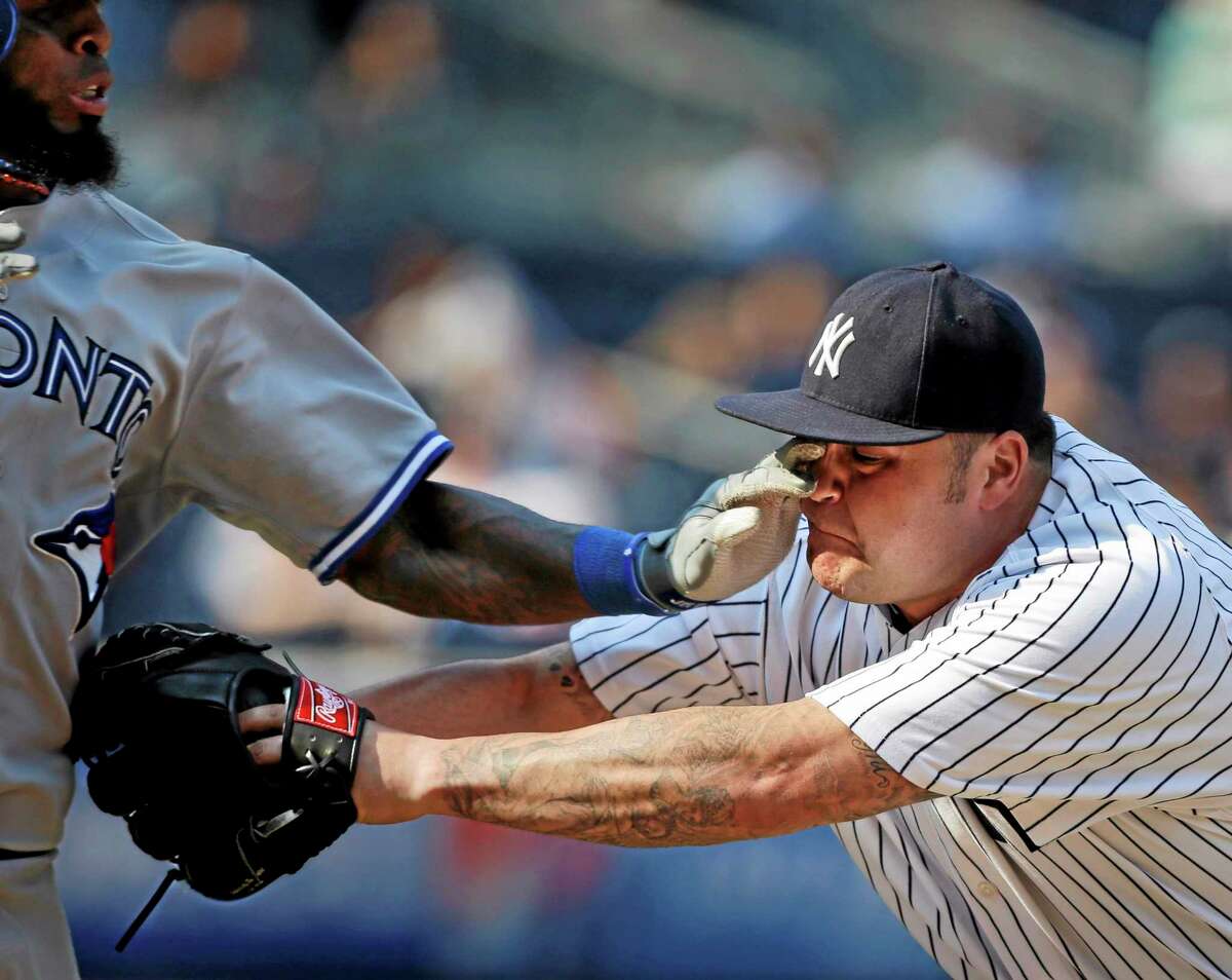 New York Yankees relief pitcher Joba Chamberlain, right, gets a hand in his eye while tagging out Toronto Blue Jays' Jose Reyes during the ninth inning in the first baseball game of a doubleheader at Yankee Stadium Tuesday, Aug. 20, 2013, in New York. (AP Photo/Seth Wenig)