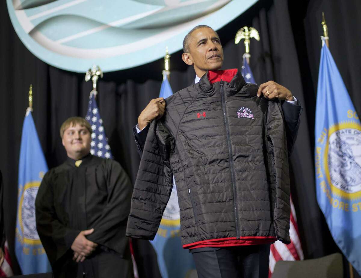 FILE - In this May 8, 2015, file photo, President Barack Obama holds up a school jacket that was gift for him by the Class of 2015 after delivering the commencement address at Lake Area Technical Institute in Watertown, S.D. Graduation season is winding down but among the eight commencement addresses given this year by three of the biggest names, President Barack Obama, first lady Michelle Obama and Vice President Joe Biden, a few moments stood out that may last a little longer. (AP Photo/Pablo Martinez Monsivias, File)