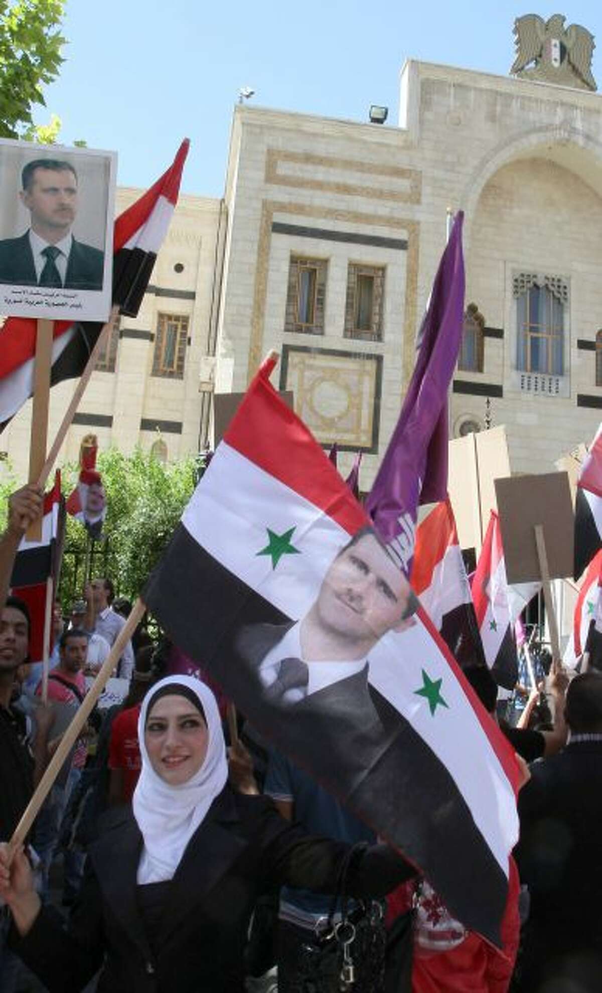 Syrians, holding up national flags and portraits of Syrian President Bashar Assad stage a sit-in before the Syrian parliament in Damascus Tuesday, Sept. 17, 2013. The sit-in was organized by the Arab Socialist Union party to protest against the U.S. and its allies? escalation against Syria.(AP Photo)