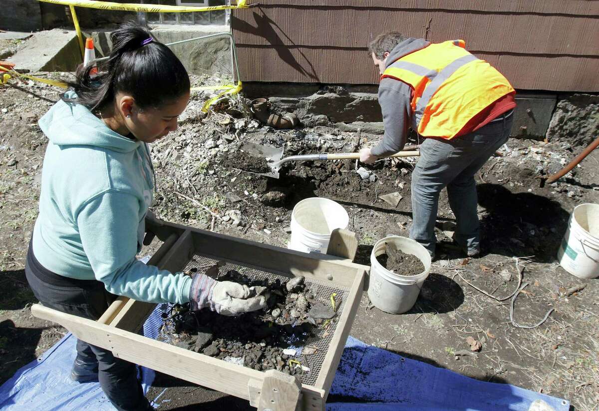 FILE - In this March 29, 2016 file photo, city archeologist Joseph Bagley, right, digs as volunteer Rosemary Pinales sifts soil for items at the house where slain African-American activist Malcolm X lived for a time with his sister's family in the 1940s in the Roxbury section of Boston, when he was known as Malcolm Little. Bagley said that a two-week dig at the home, in an effort to learn more about his early life, uncovered evidence of an older settlement dating to the 1700s that they hadn't expected to find. After weather delays, the dig is set to resume on May 16. (AP Photo/Bill Sikes, File)