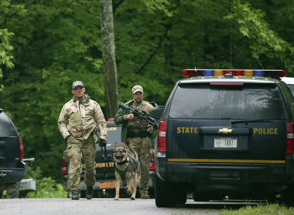Law enforcement officers walk along a road on Sunday, June 28, 2015, in Malone, N.Y. The shooting death of one escaped killer brought new energy to the three-week hunt for a second escaped murderer in the United States as helicopters, search dogs and hundreds of law enforcement officers converged on a wooded area 30 miles from Clinton Correctional Facility. (AP Photo/Mike Groll)