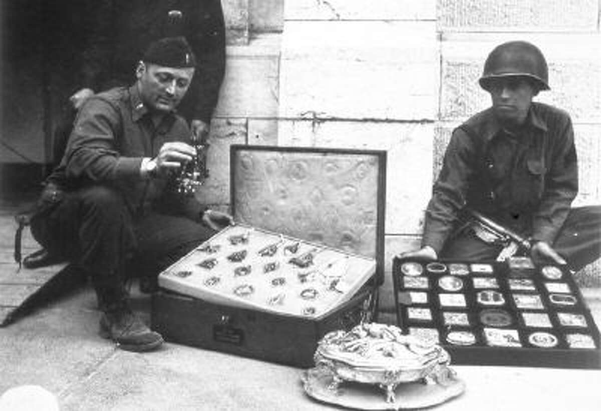 This photo provided by The Monuments Men Foundation for the Preservation of Art of Dallas, shows Monuments Man James Rorimer, left, and Sgt. Antonio Valim examining valuable art objects at Neuschwanstein Castle in Germany which were stolen from the Rothschild collection in France by the ERR and found in the castle in May of 1945.