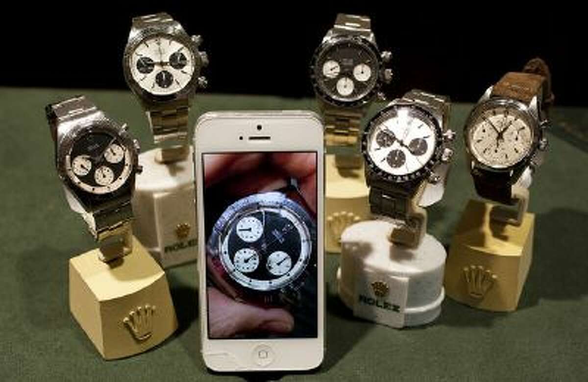 A photo of a Paul Newman Rolex Daytona on Kris Bonifas' iPhone sits with an actual Rolex Daytona's at left, and other Rolex watches at FourtanÈ in Carmel-by-the-Sea, Calif., on Thursday, July, 11, 2013.