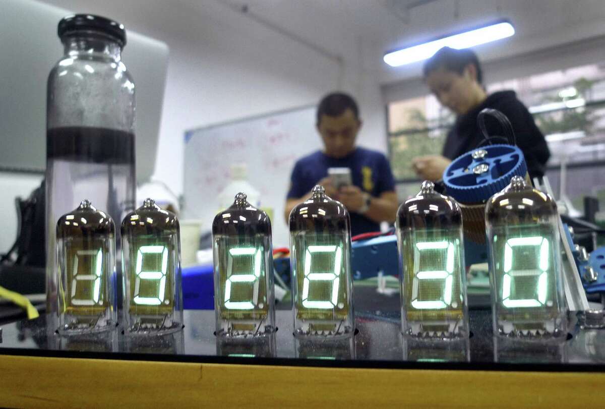 (Kelvin Chan — The Associated Press) Eric Pan founder of Seeed Technology, a contract manufacturer for “makers” — tinkerers, hackers and inventors — talks with a friend while a homemade digital clock is seen in the foreground in Shenzhen, China.