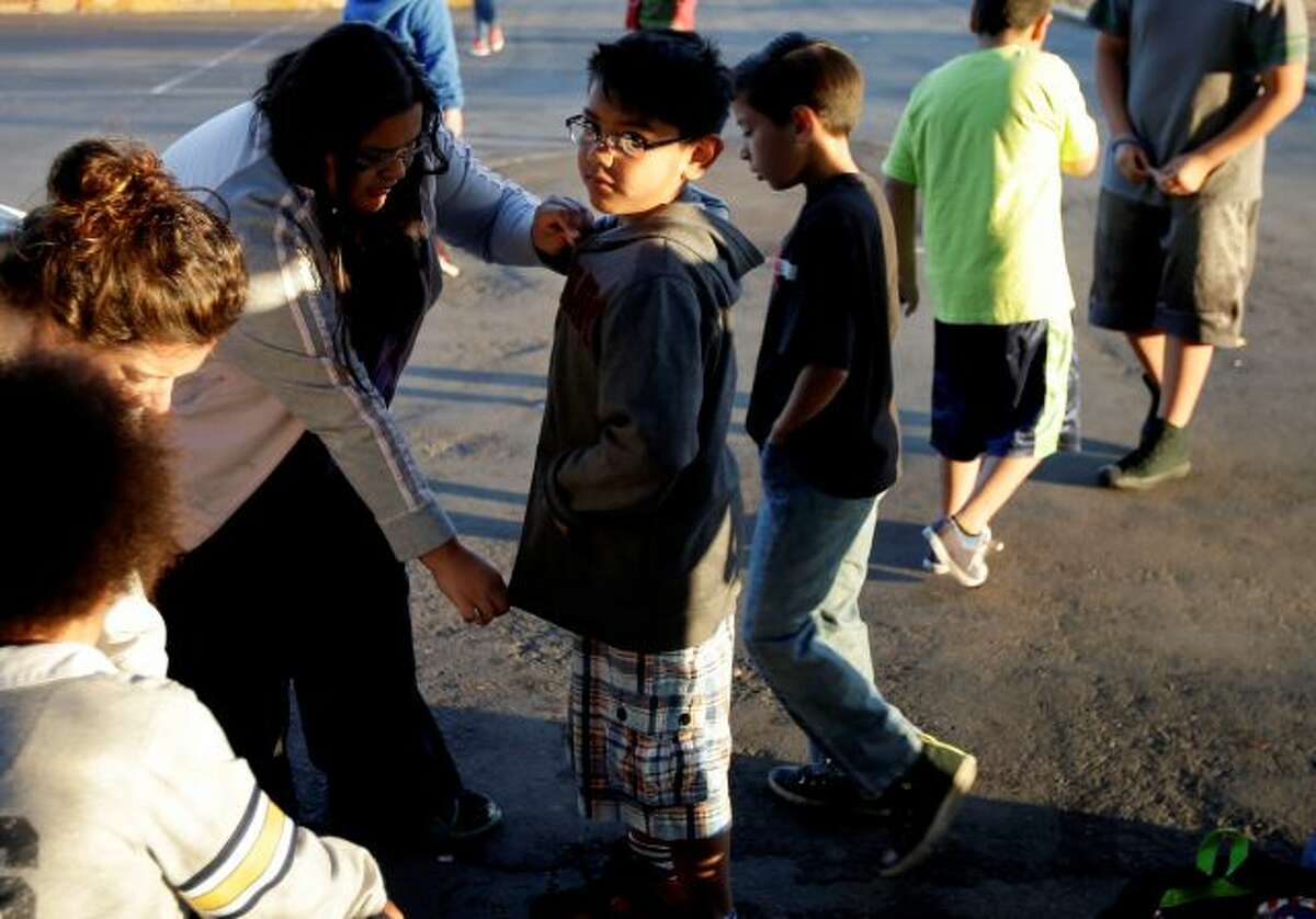 In this March 14, 2014 picture, Marina Beltran, left, zips up the jacket of her son Antonio before he takes part in an early morning running program at his elementary school in Chula Vista, Calif. Amid alarming national statistics showing an epidemic in childhood obesity, hundreds of thousands of students across the country are being weighed and measured. Beltran son's Chula Vista Elementary School District is being touted as a model for its methods that have resulted in motivating the...