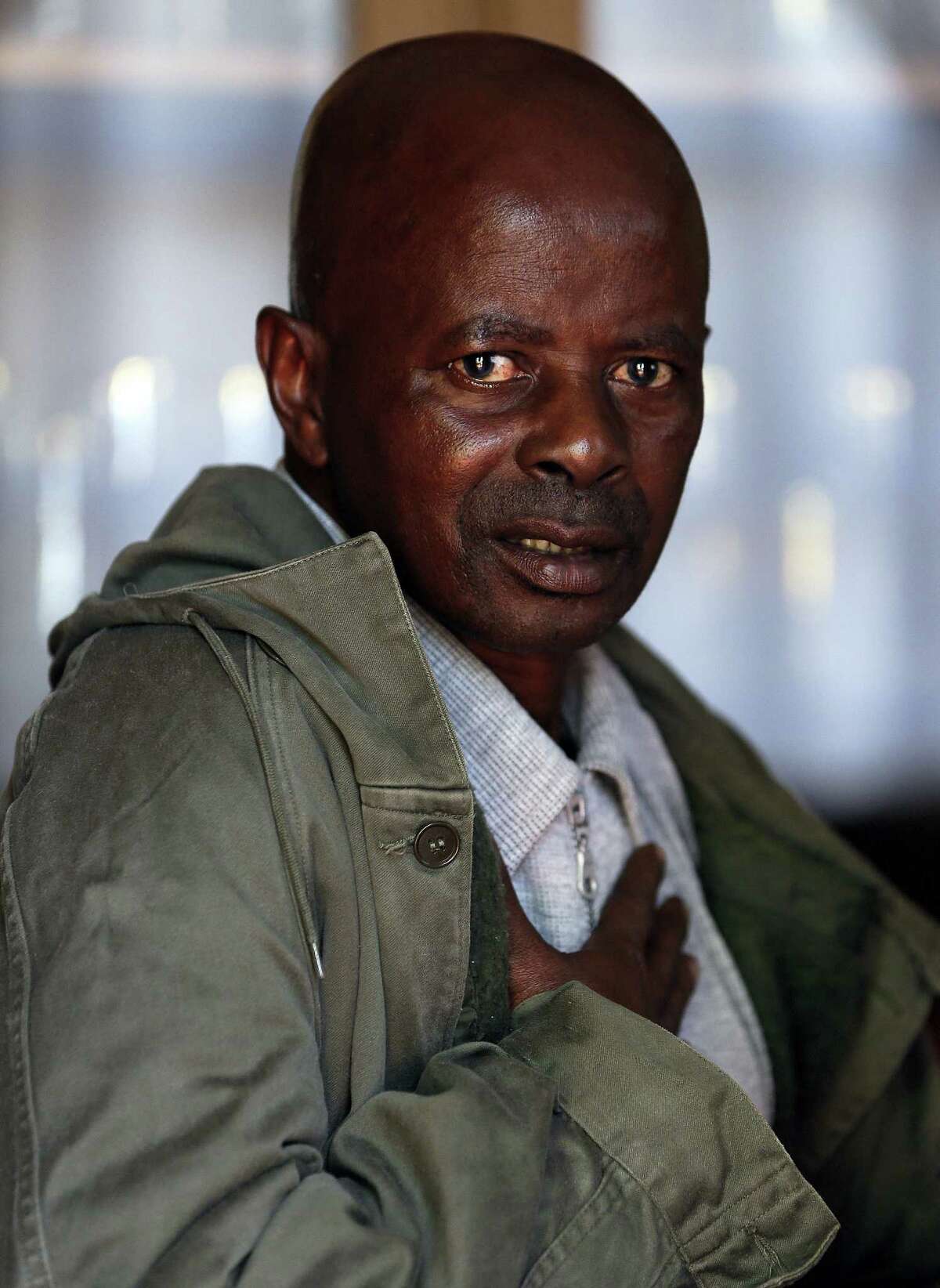 Former mine worker Tshidiso Thulo holds his chest as he sits in his lounge in Welkom, South Africa.