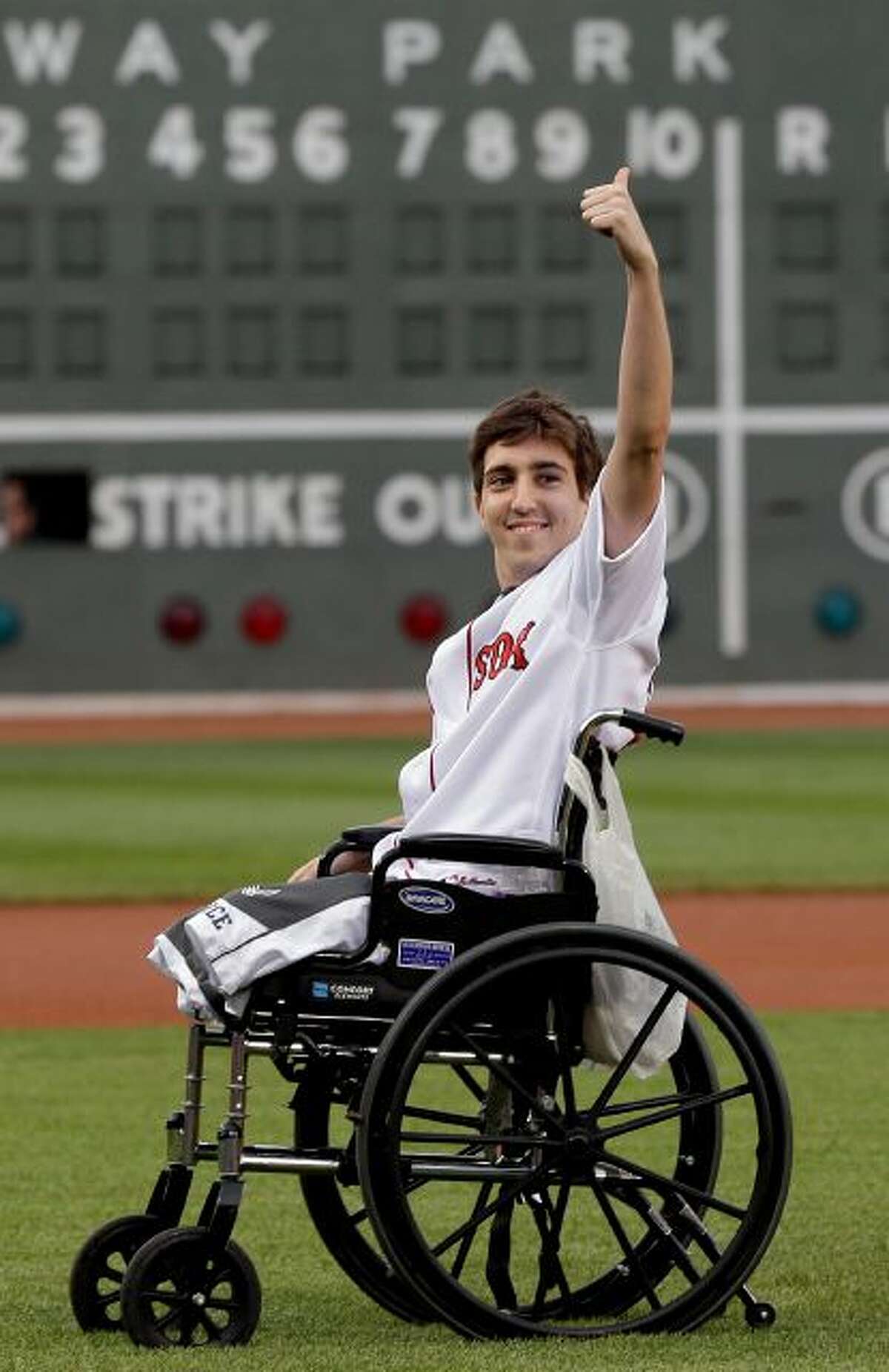 This May 28, 2013 file photo, Boston Marathon bombing survivor Jeff Bauman acknowledges cheering fans before throwing out a ceremonial first pitch at Fenway Park prior to a baseball between the Boston Red Sox and the Philadelphia Phillies in Boston. Bauman, who lost both legs in the Boston Marathon bombings, then helped authorities identify the suspects, is engaged and an expectant father. Bauman and his fiancé, Erin Hurley, tell The Associated Press that the baby is due July 14. They...