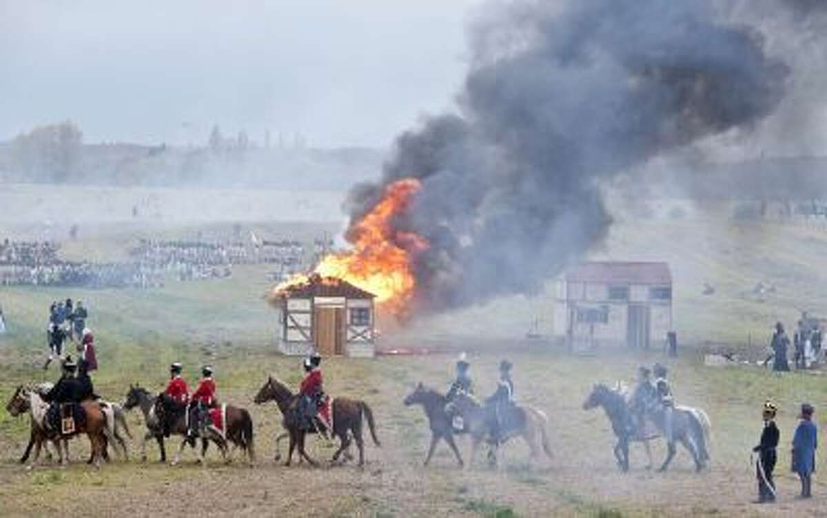 Troops march in front of a burning house during the reconstruction of the Battle of the Nations at the 200th anniversary near Leipzig, central Germany, Sunday, Oct. 20, 2013.