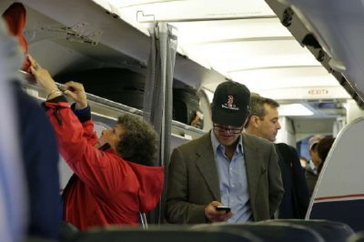 In this Thursday, Oct. 31, 201 file photo, a passenger checks his cell phone while boarding a flight, in Boston.