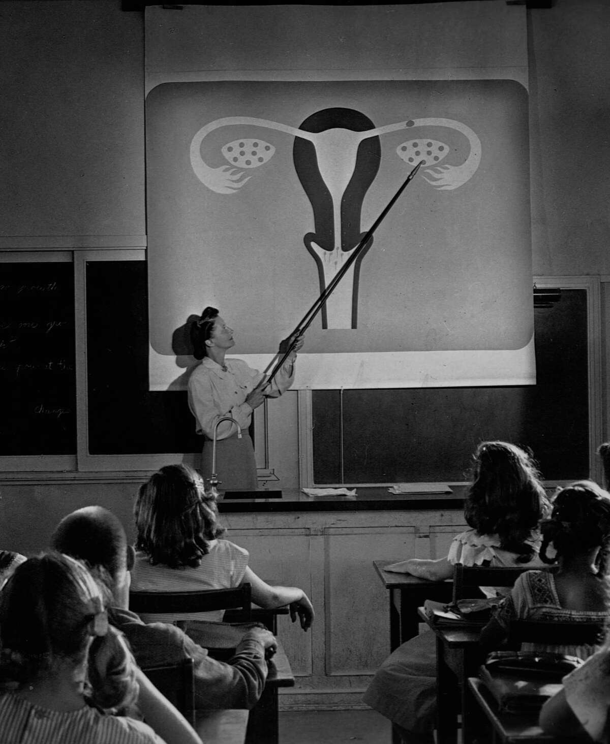 A teacher points to a diagram of female reproductive organs projected on a screen in a classroom in a scene from Human Growth, an education film on sex education shown to students in Oregon junior high schools beginning in 1948. (Photo by Library of Congress/Corbis/VCG via Getty Images)