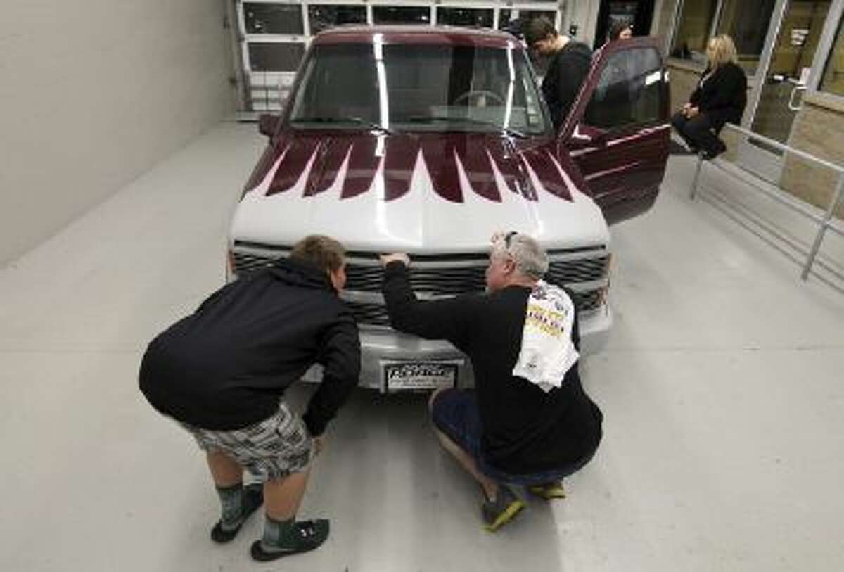 In this Oct. 17, 2013 photo, Rich Vahle, right, and his son, Lane, pop the hood of a customized 1993 Chevrolet Silverado pickup truck at Poage Auto Plaza in Quincy, Ill. The truck once belonged to Rich's father, Dan, who died of cancer in 1997, and was returned to the family.