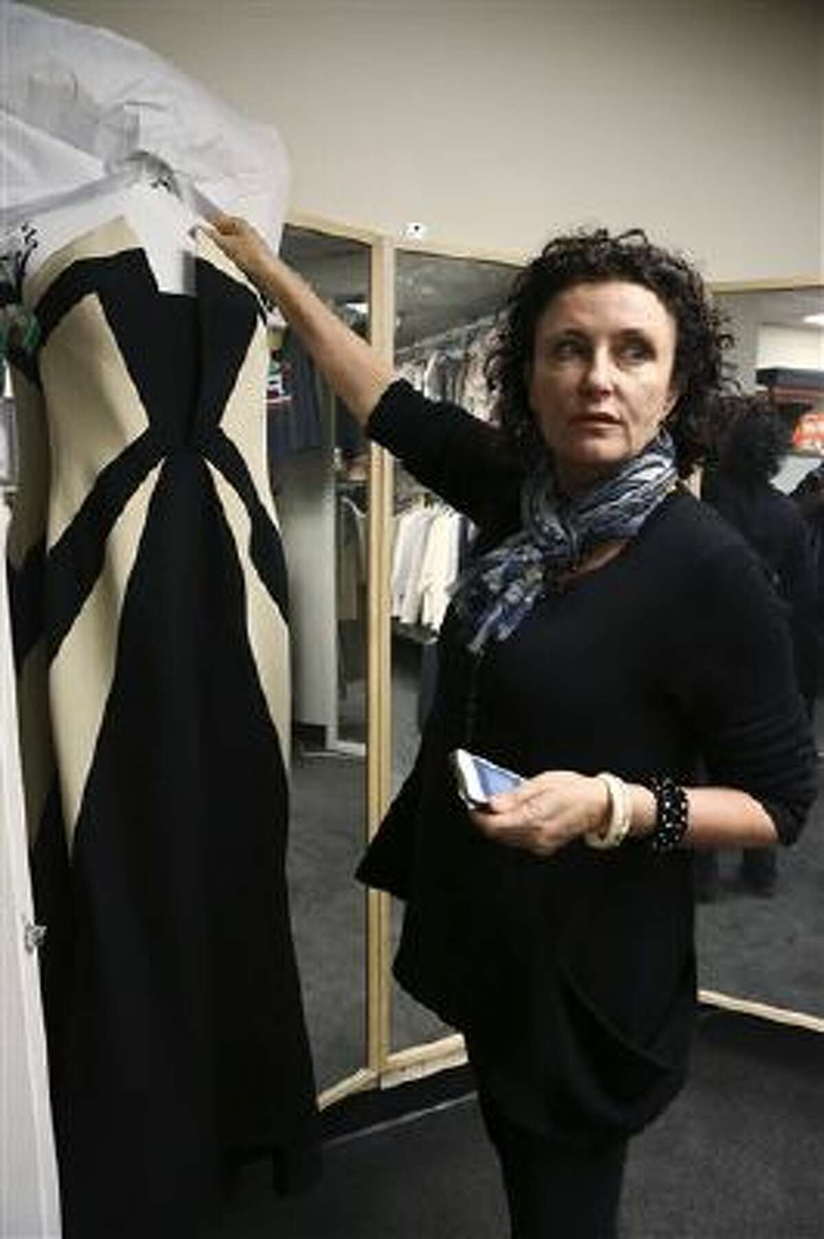 In this Nov. 11, 2013 image released by ABC, Lyn Paolo, costume designer holds a Rubin Singer gown worn by Kerry Washington in the ABC drama series, "Scandal," in the show's wardrobe closet on the Sunset Gower lot in the Hollywood section of Los Angeles.