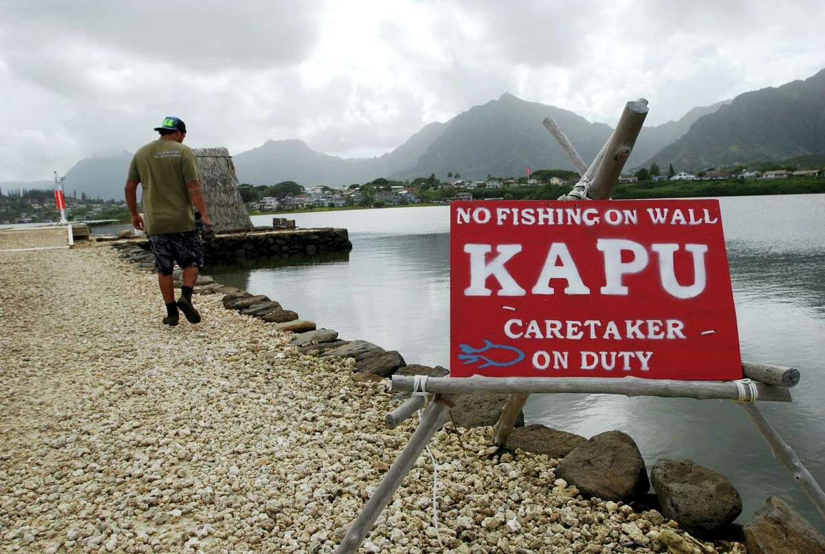 In this Friday, Dec. 2, 2016 photo, Conservation International's Luka Mossman, who restores and researches Native Hawaiian fishponds, walks along a barrier wall on Heeia fishpond in Kaneohe, Hawaii. As traditional commercial fishing is threatening fish populations worldwide, U.S. officials are working on a plan to expand fish farming into federal waters around the Pacific Ocean. Some see the move toward aquaculture as a promising solution to overfishing and feeding a hungry planet. But critics say the industrial scale farms could do more harm than good to overall fish stocks and ocean health. (AP Photo/Caleb Jones)