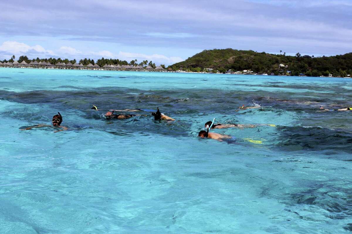 This Nov. 2, 2016 photo shows tourists snorkeling in the lagoon in Bora Bora as part of a tour. Bora Bora offers celebrity-style seclusion and has been a vacation destination for the likes of Justin Bieber, Jennifer Aniston and Usain Bolt. It's located 160 miles from Tahiti with a balmy and relatively consistent temperature of 80 degrees Fahrenheit. (AP Photo/Jennifer McDermott)